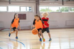Niños y niñas jugando en las clases de baloncesto para colegios